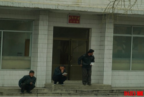 元山市内の交通安全教養室の前で交通安全教本を手に持ち喫煙する人々。交通違反を摘発され再教育を受けている。（画像：デイリーNK内部情報筋）